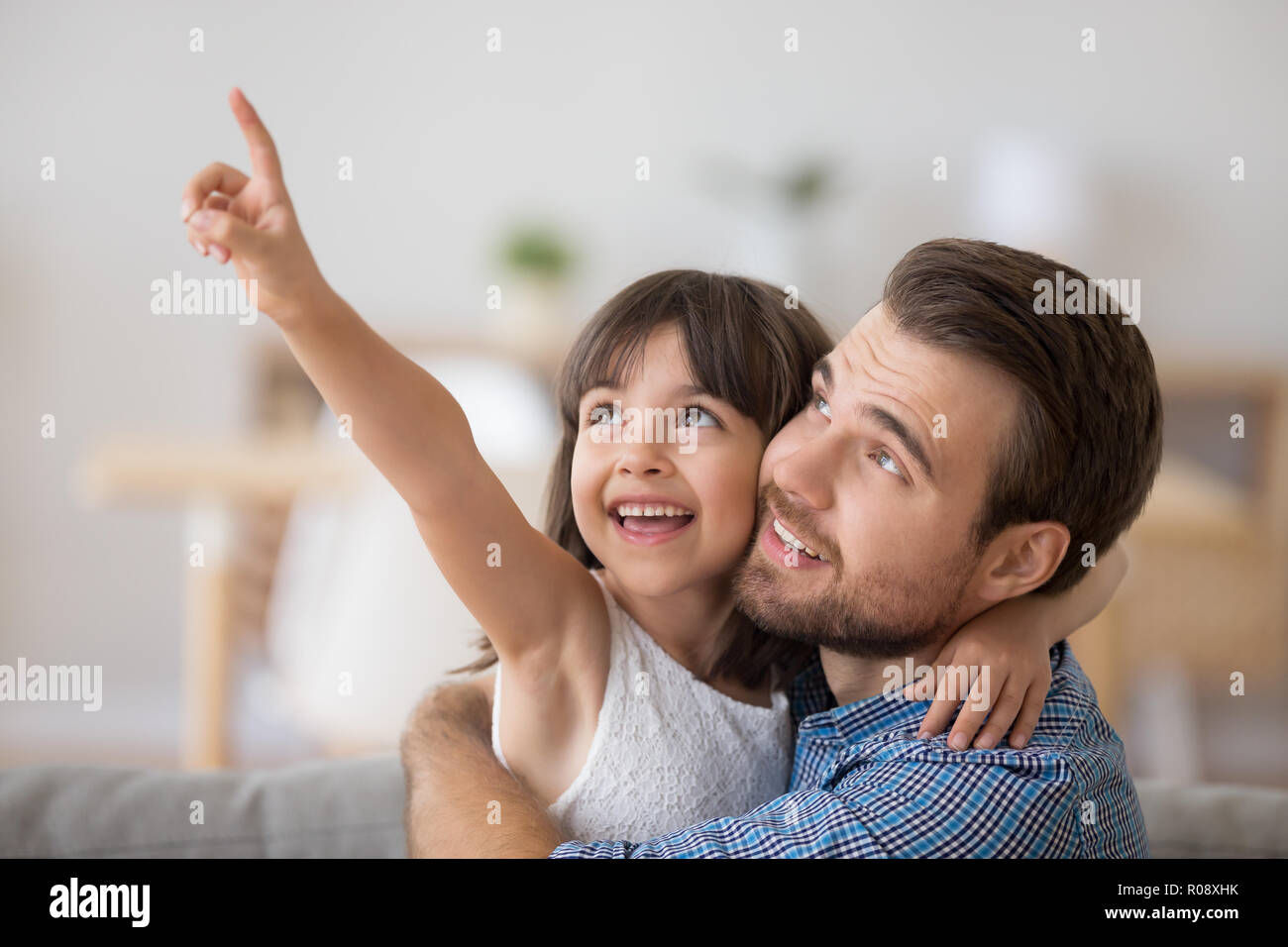 Daughter embracing with father pointing with her hand upper left Stock Photo