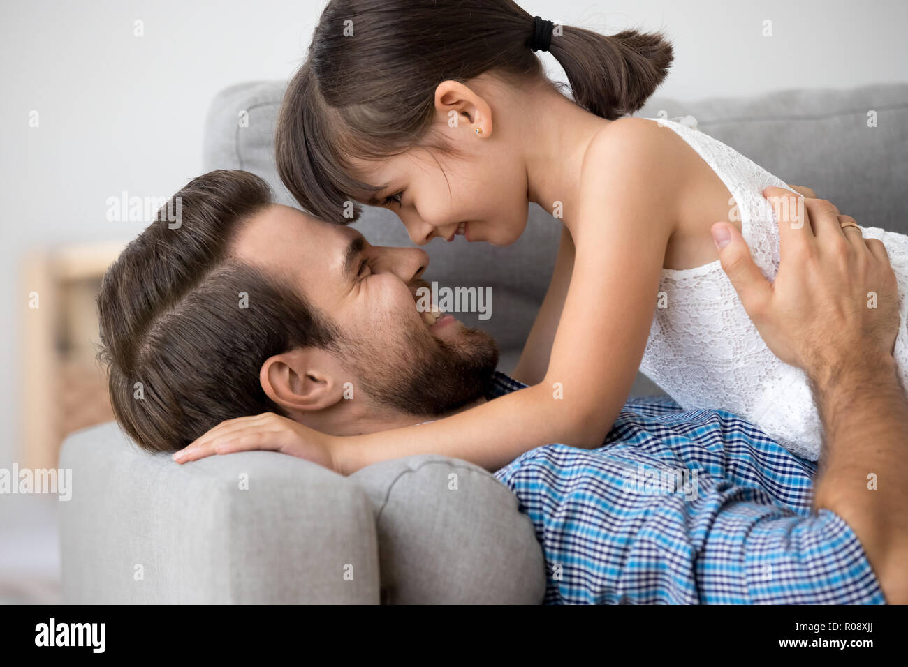 Daughter and father smiling lying together on couch Stock Photo