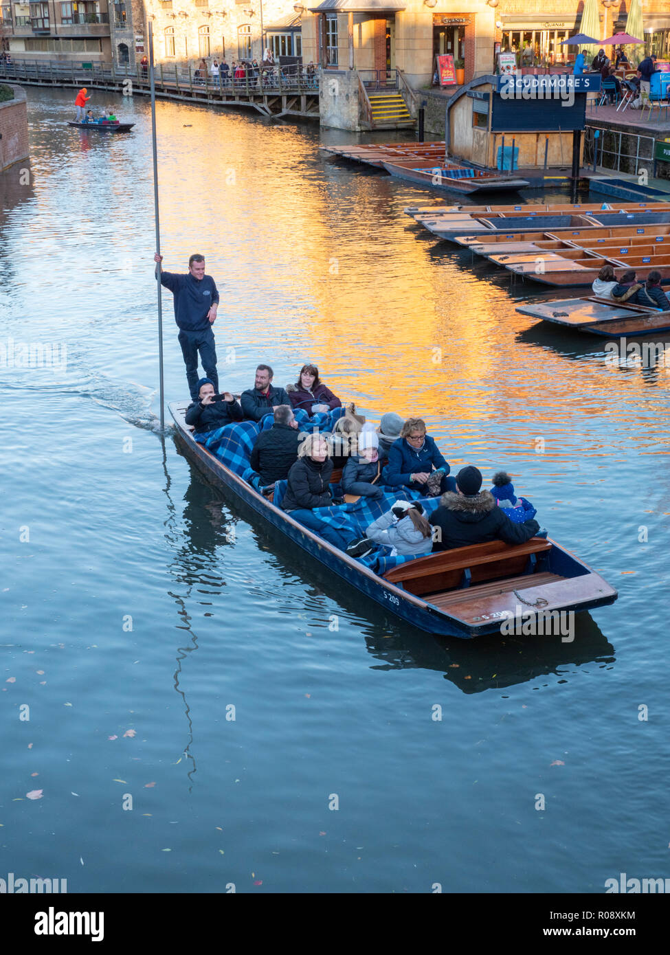 A chauffeured punt with a group of tourists on a punt trip  on the River Cam Cambridge UK near Quayside at sunset in winter Stock Photo