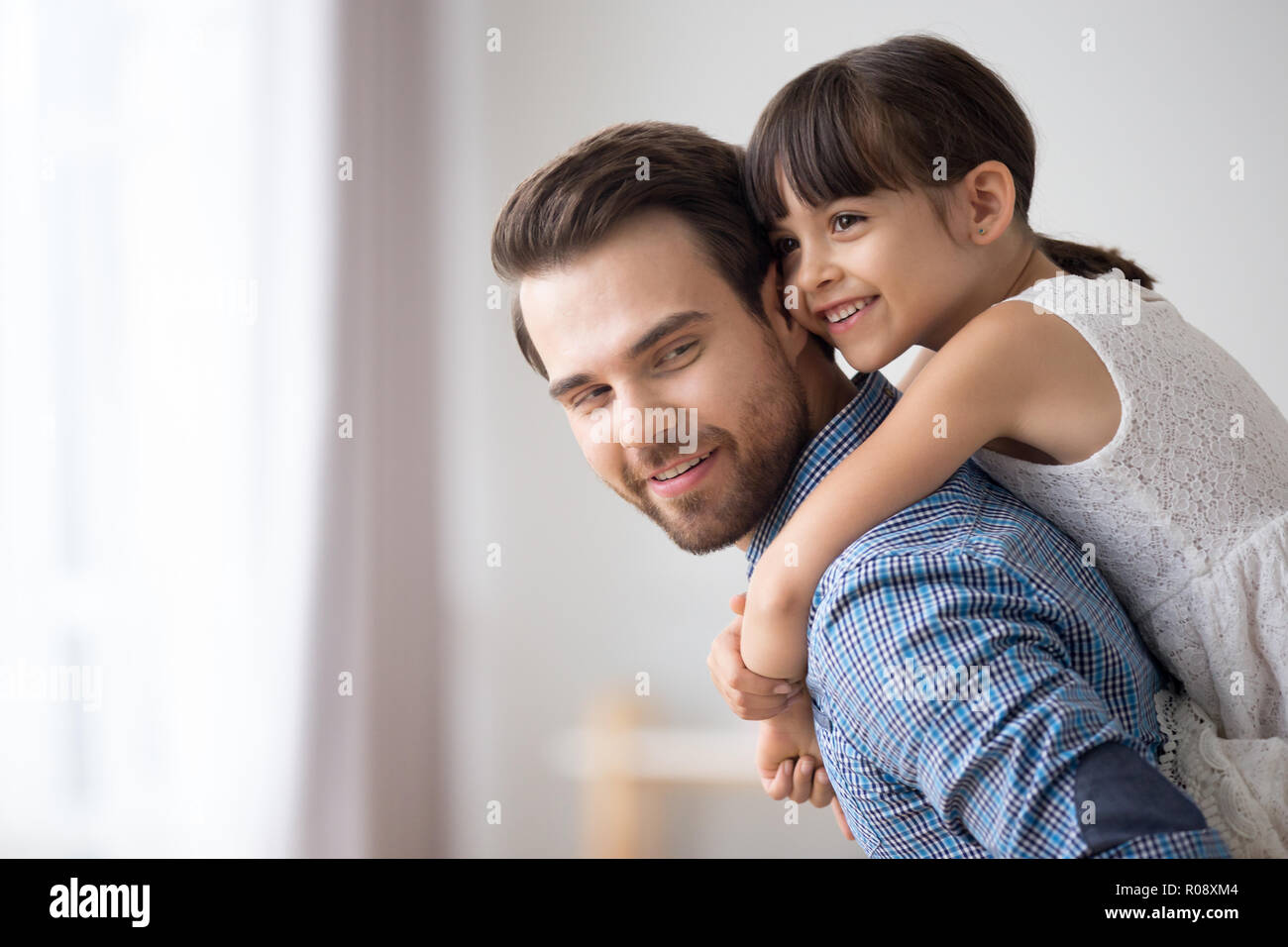 Father hold daughter piggyback standing in living room Stock Photo
