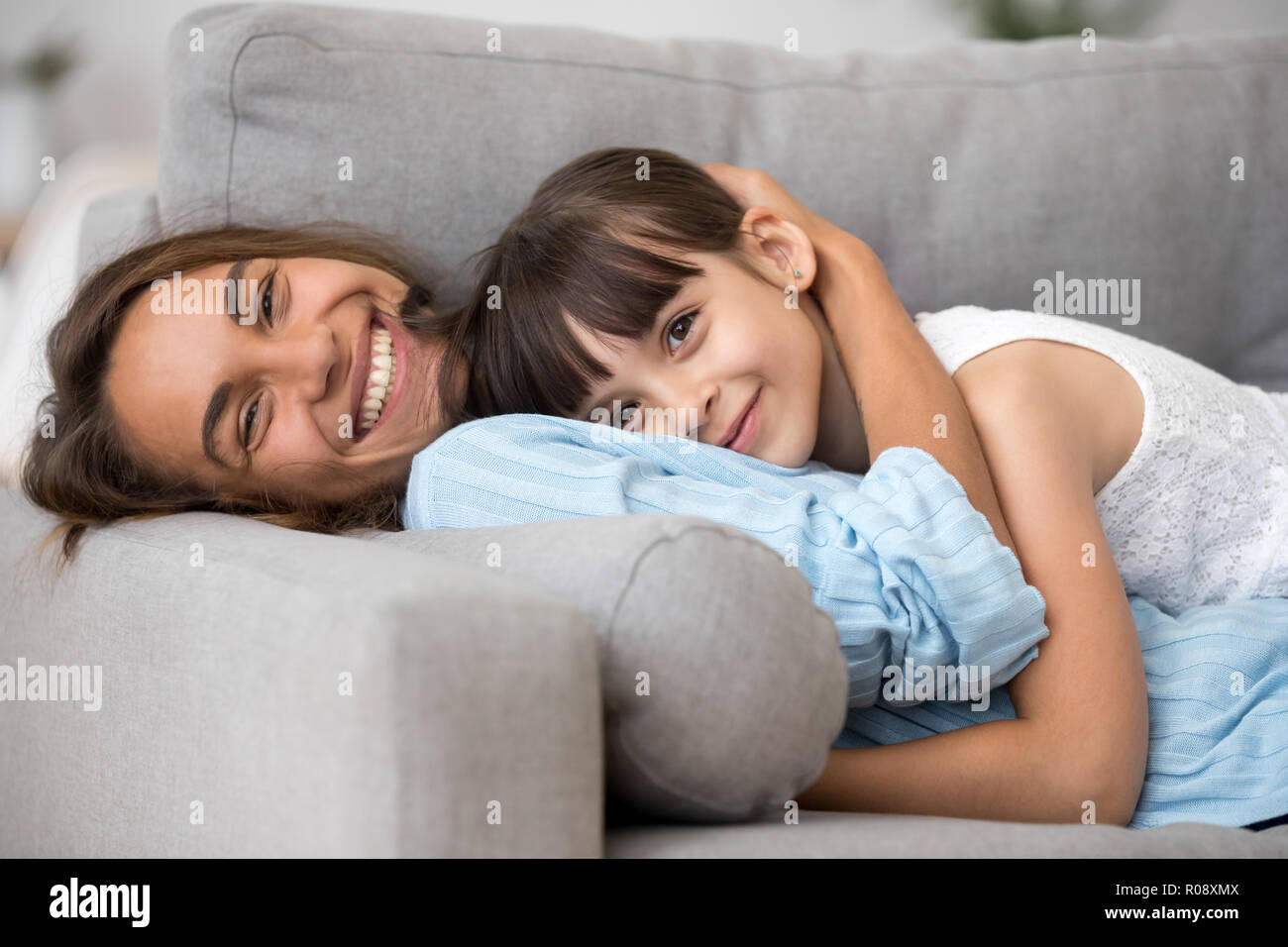 Happy mother and adorable daughter lying on sofa Stock Photo