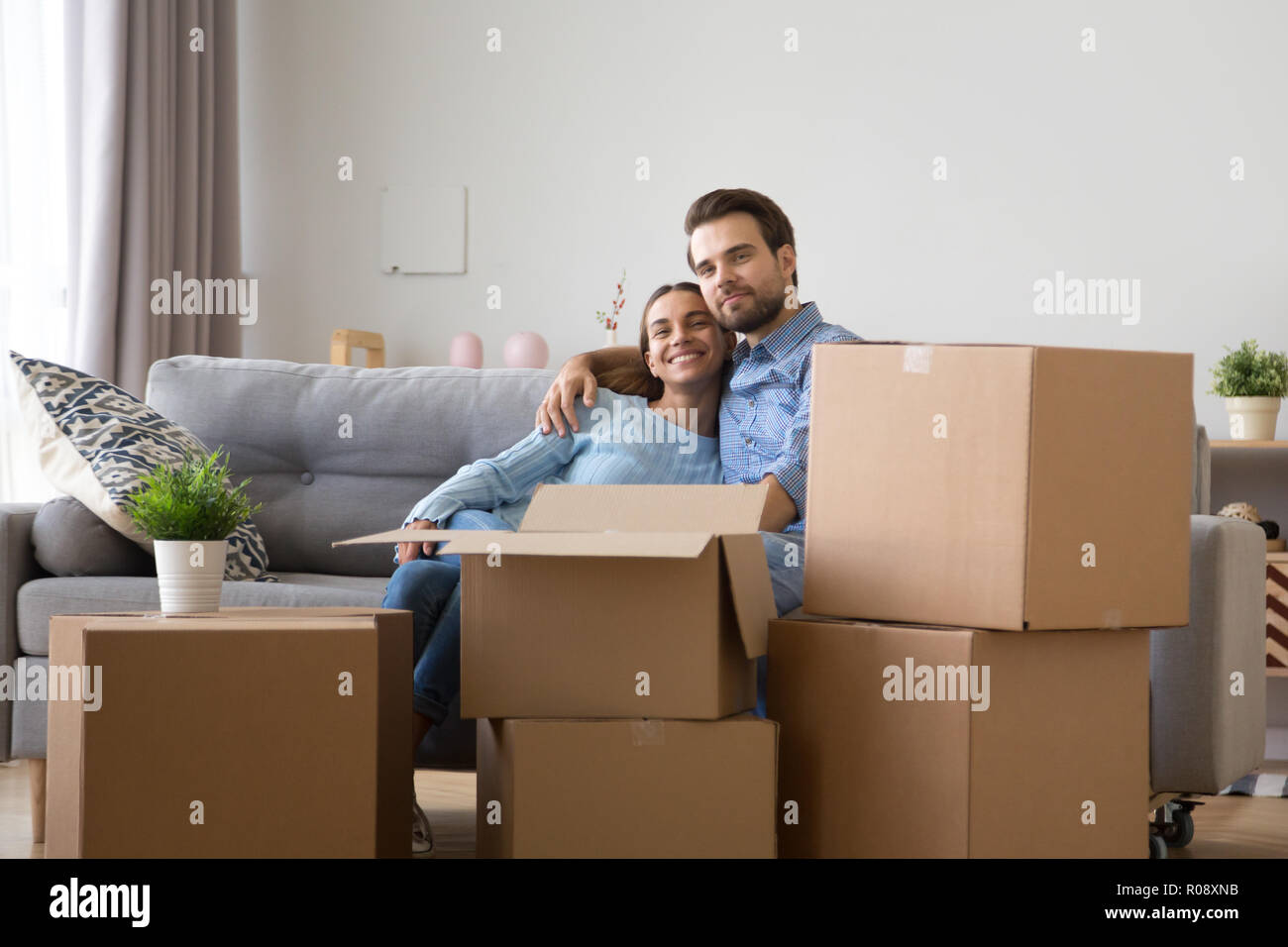 Diverse family sitting on couch at new home  Stock Photo