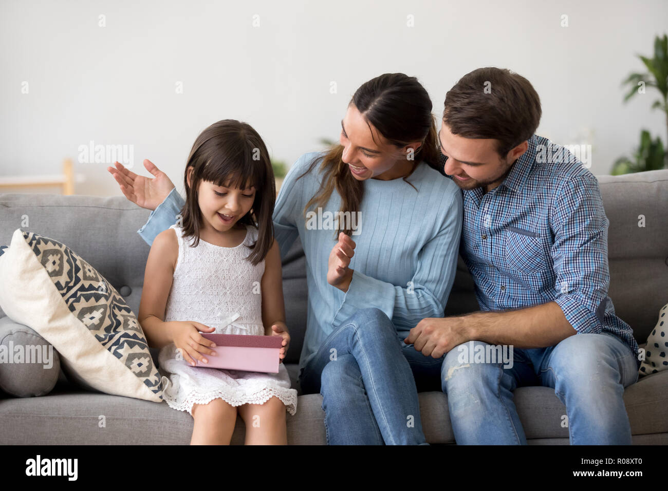 Parents congratulate loving daughter sitting together on couch Stock Photo