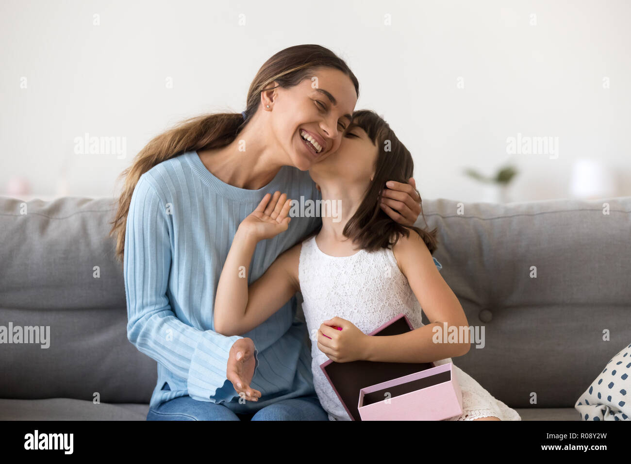Grateful daughter receives from mother gift kissing her Stock Photo
