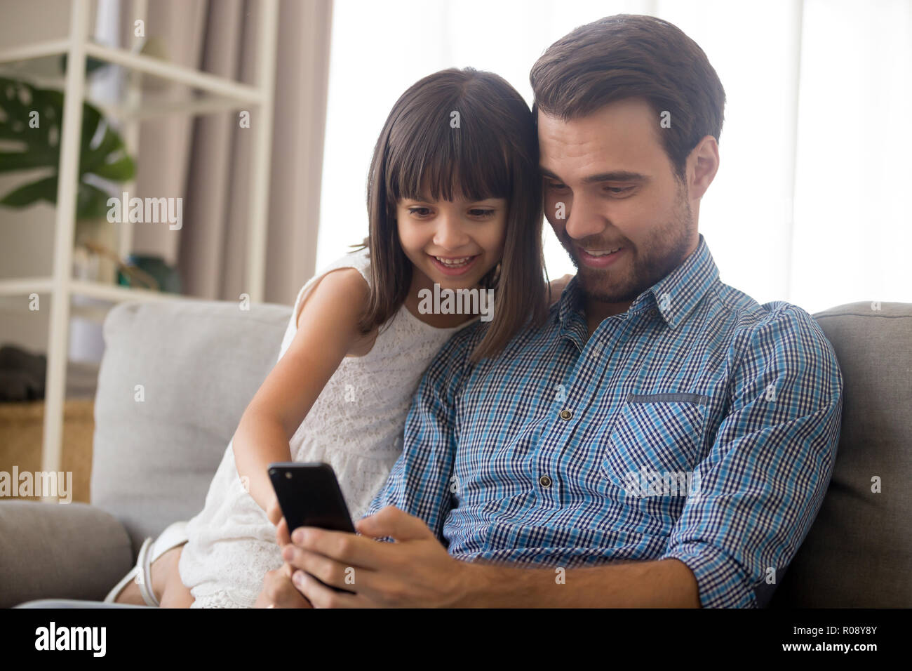 Father and little daughter spend free time using smartphone Stock Photo