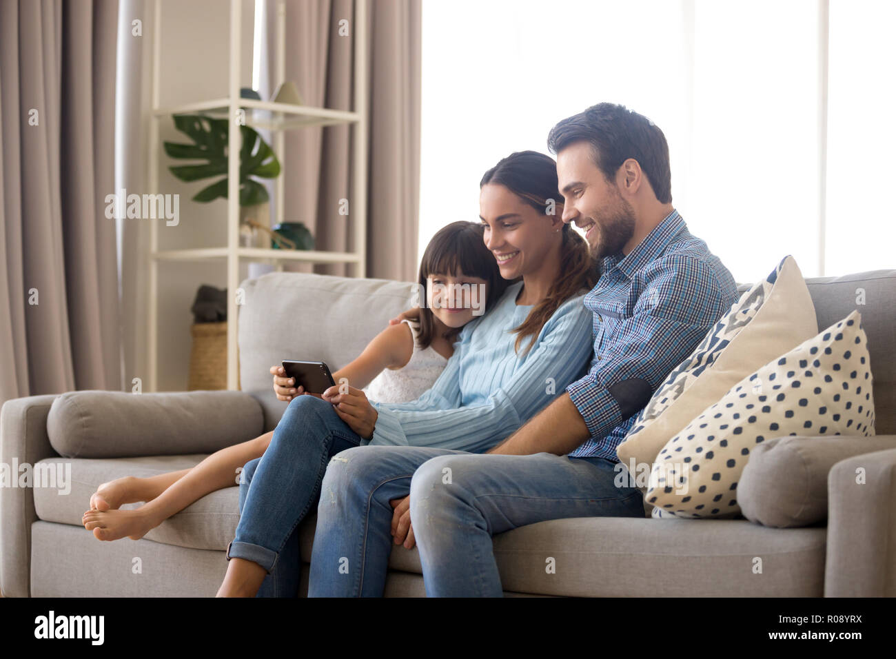 Family spend free time watching cartoons on mobile phone Stock Photo