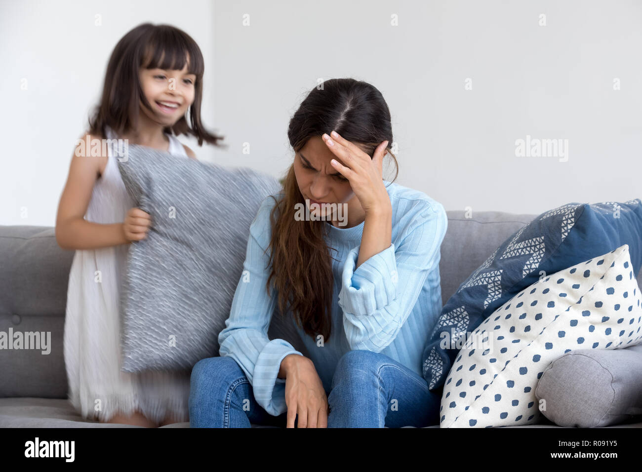 Daughter have fun play with cushion her mother feels unwell Stock Photo