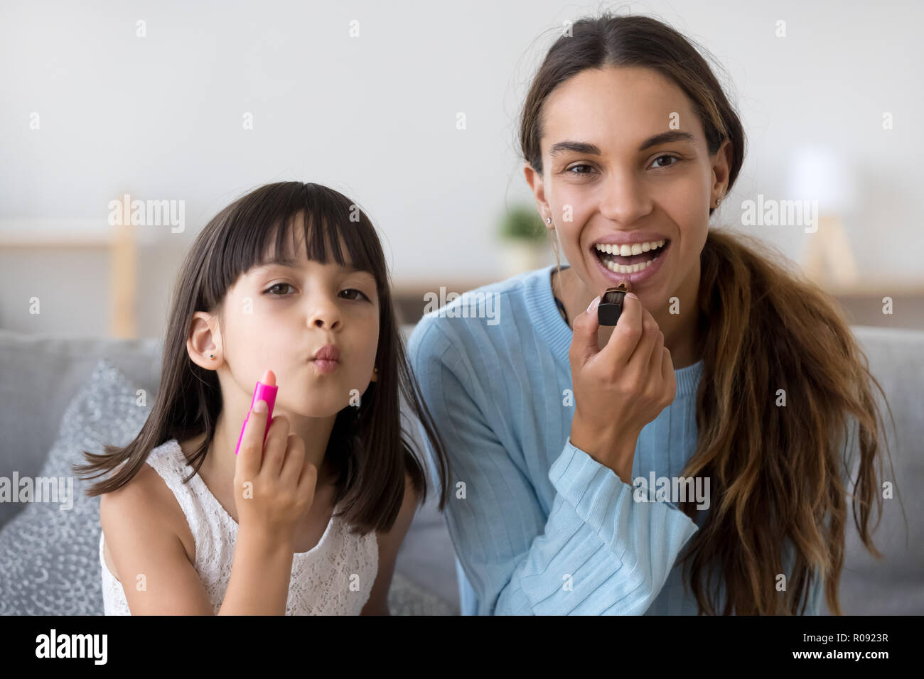 Headshot portrait mother and daughter applying lipstick Stock Photo