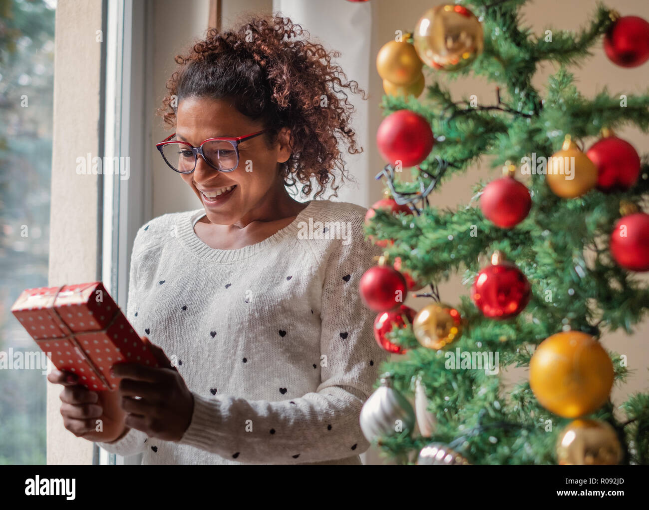 Happy black woman opening christmas presents at home Stock Photo