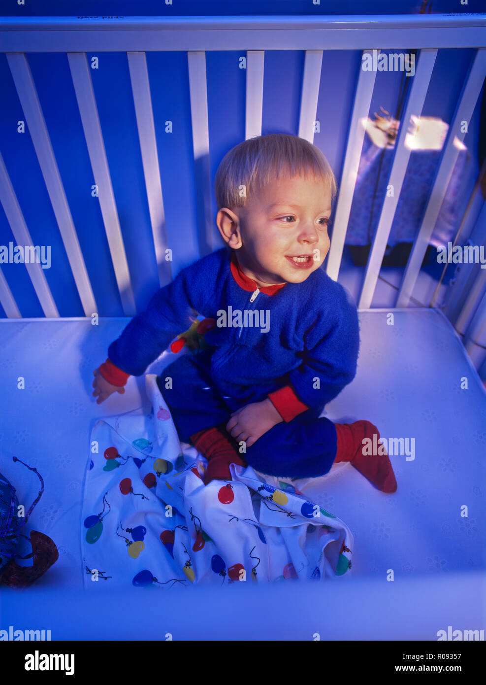 Baby in a crib at night who is having trouble going to sleep and sleeping Stock Photo