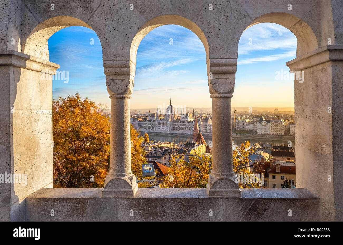 Budapest, Hungary - The beautiful Hungarian Parliament building through old windows of Buda District at sunrise with autumn foliage Stock Photo