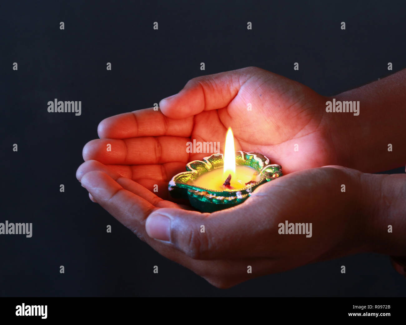 A girl holding a plate of diya to celebrate diwali hires stock
