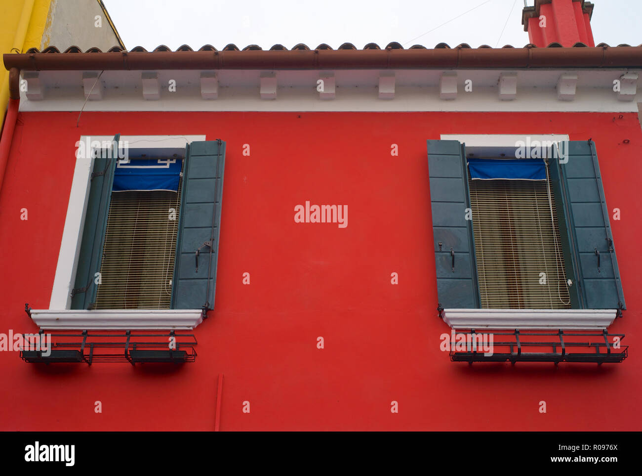 Two Windows with Green Shutters on a Bright Red Wall - The Famous Colorful Houses of Burano, Venice, Italy Stock Photo