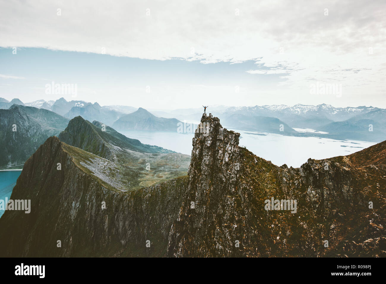 Norway mountaineering travel man standing on cliff mountain top above fjord adventure climbing extreme lifestyle journey vacations aerial view landsca Stock Photo