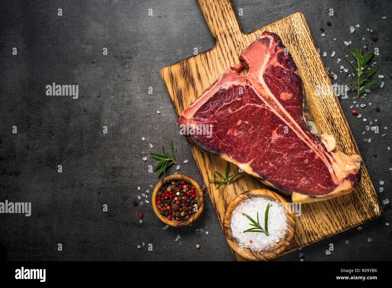 T-bone beef steak on black background with spices. Top view with copy space. Stock Photo