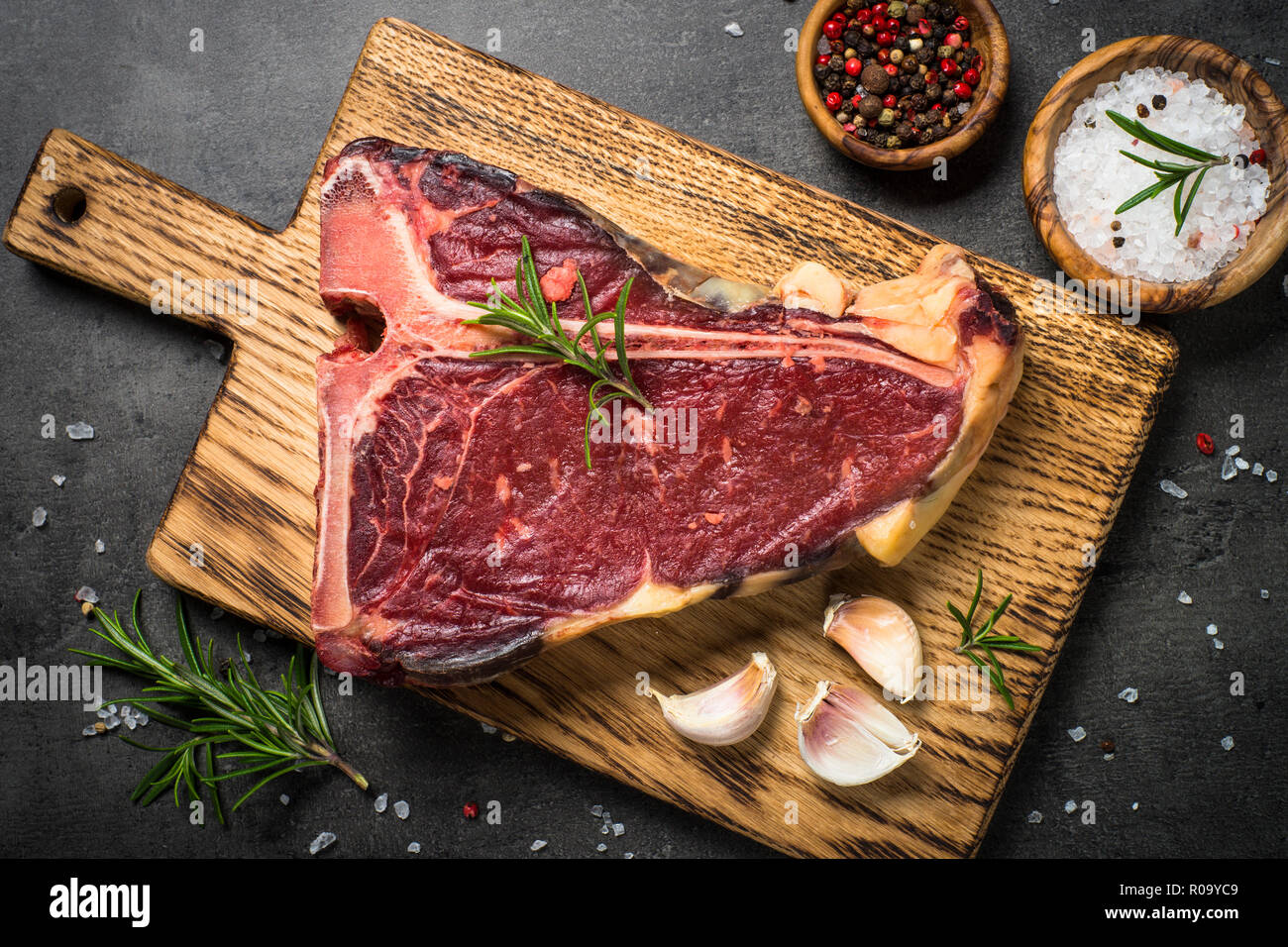 T-bone beef steak on black background with spices. Top view. Stock Photo