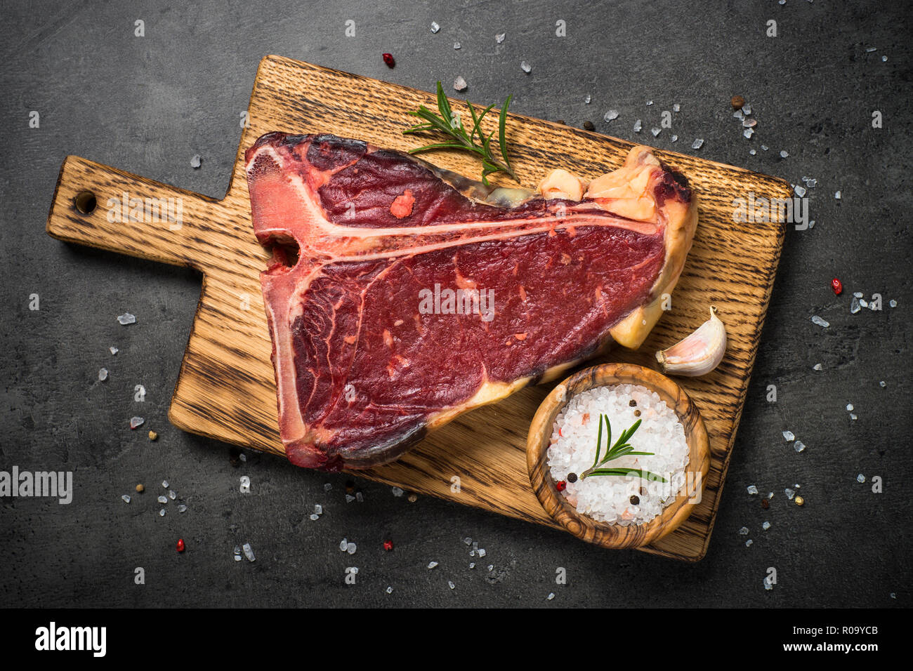 T-bone beef steak on black background with spices. Top view. Stock Photo