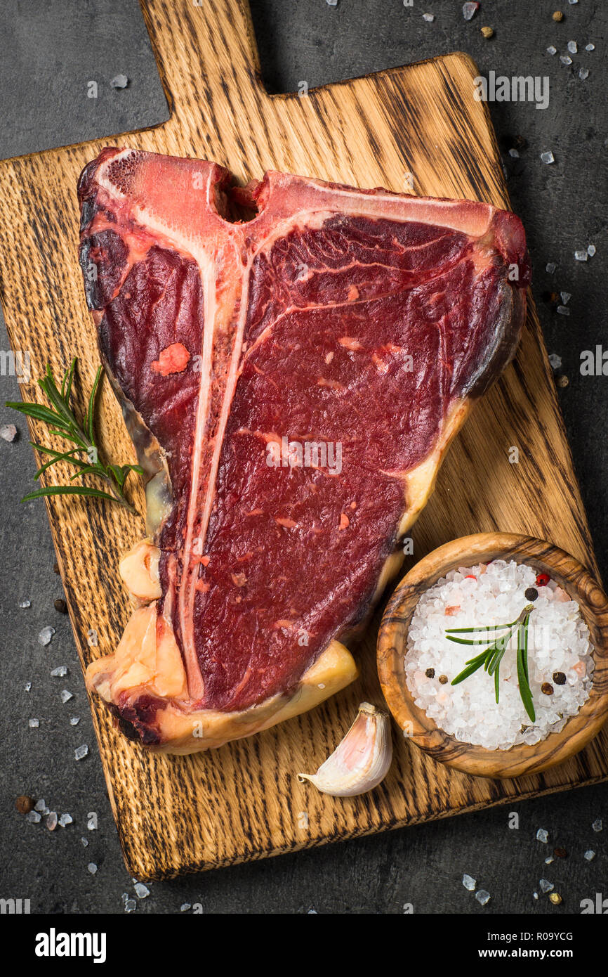 T-bone beef steak on black background with spices. Ready for cooking. Top view vertical. Stock Photo