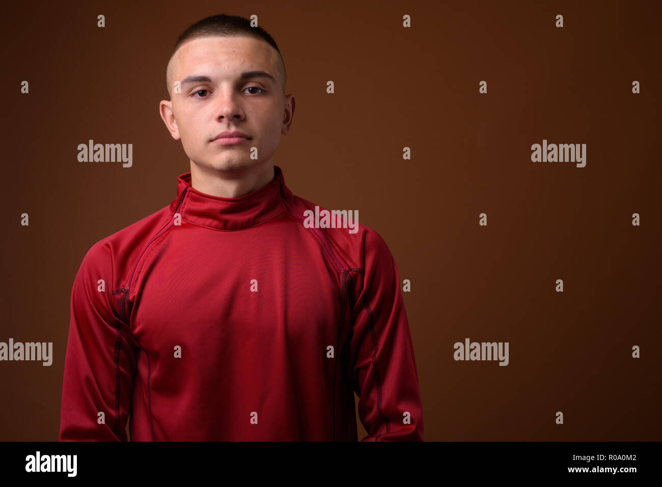 Studio shot of young handsome man with short hair against brown  Stock Photo