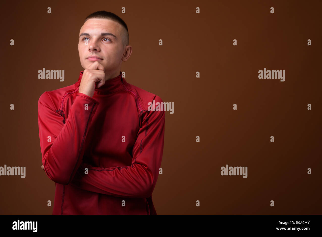Studio shot of young handsome man with short hair against brown  Stock Photo