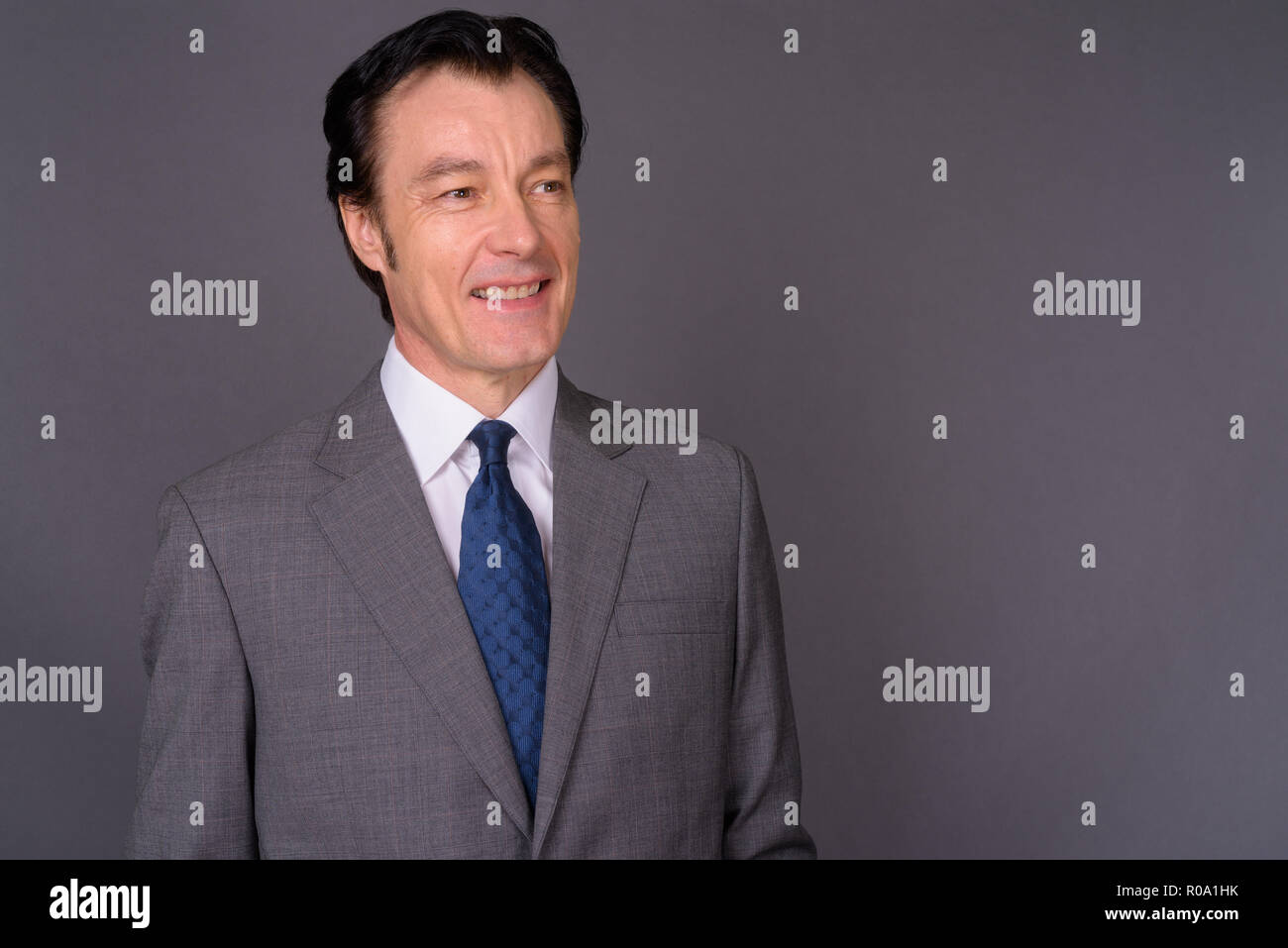 Portrait of mature handsome businessman against gray background Stock ...