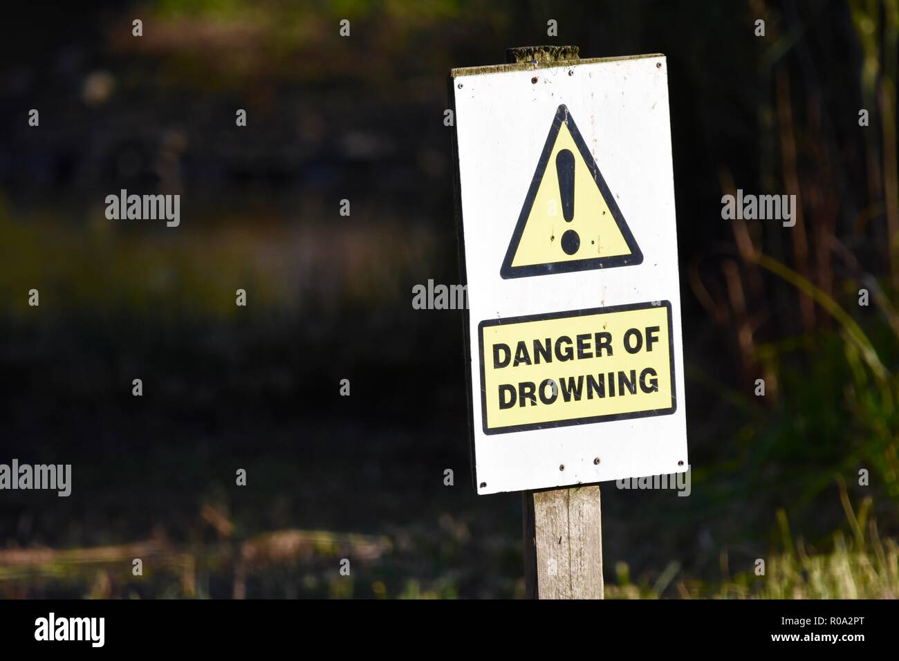 Danger of drowning sign post next to lake Stock Photo
