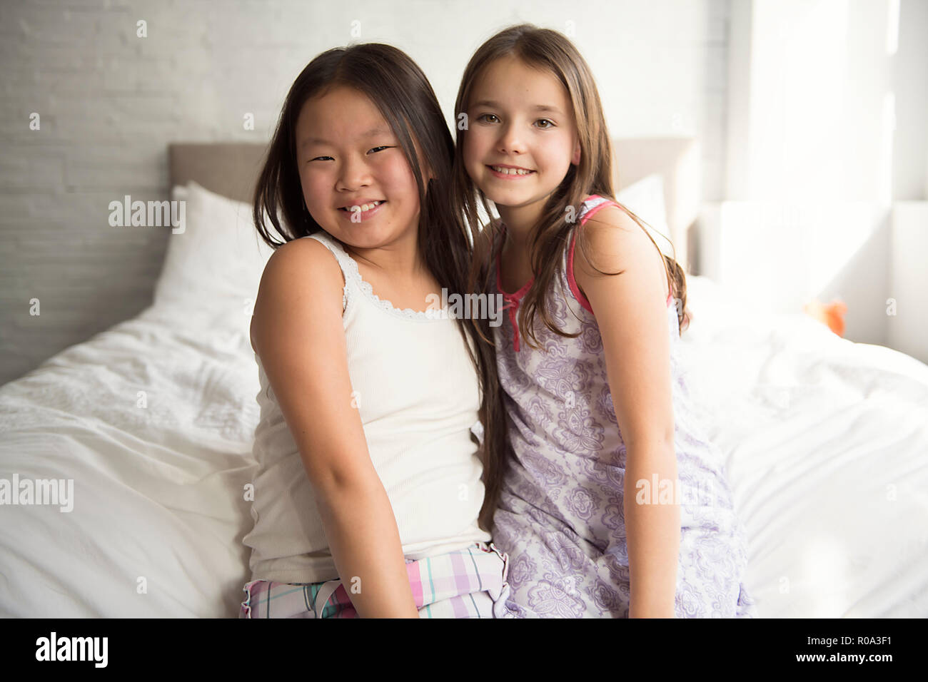 The Two little girls lying on bed at home Stock Photo