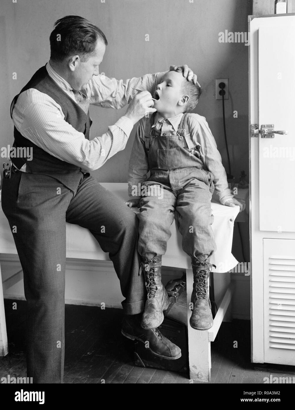 Doctor Examining Boy's Throat, Reedsville, West Virginia, USA, Elmer Johnson, Farm Security Administration, April 1935 Stock Photo