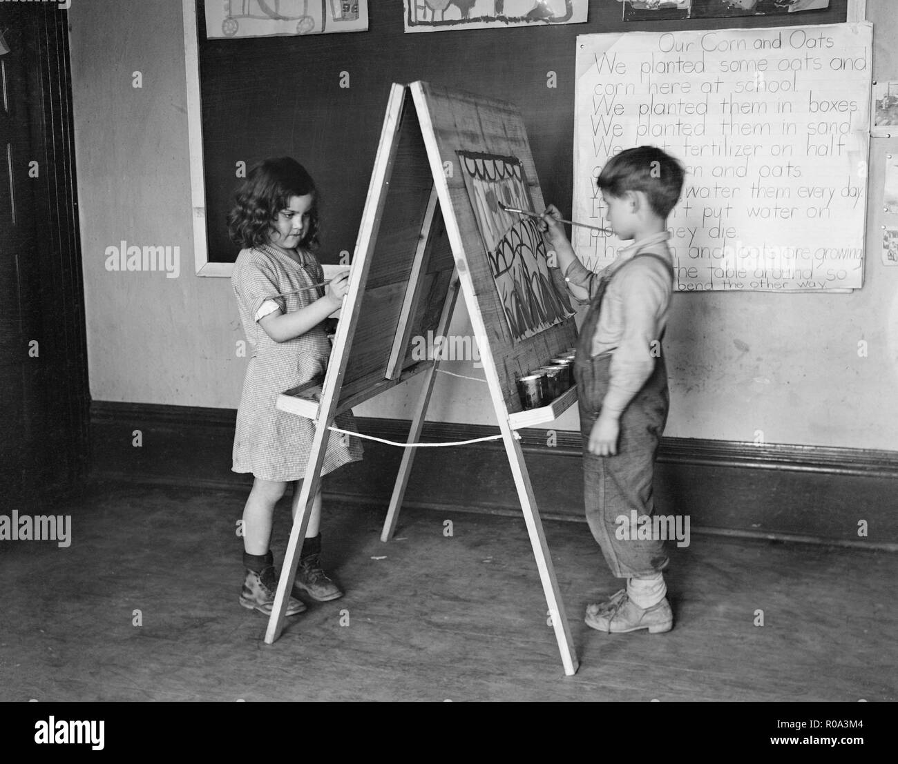 Boy and Girl Painting on Classroom Easel, Reedsville, West Virginia, USA, Elmer Johnson, Farm Security Administration, April 1935 Stock Photo