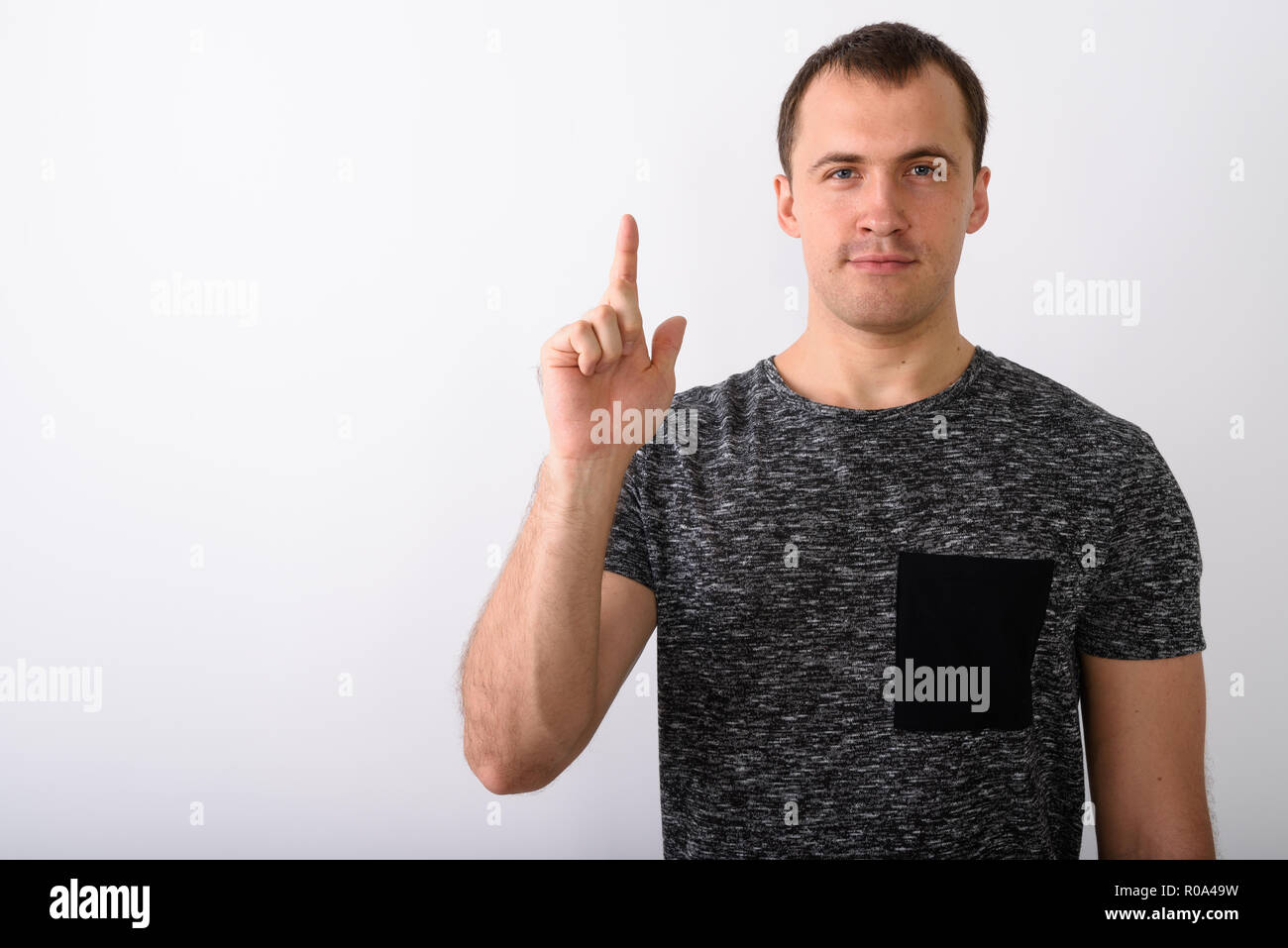 Studio shot of young muscular man pointing finger up against whi Stock Photo