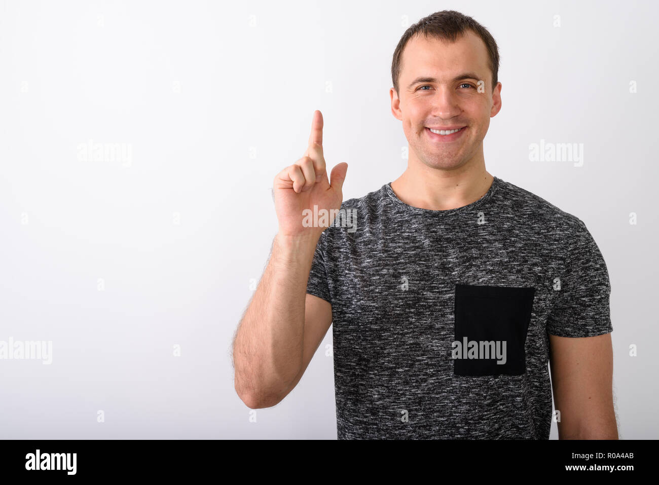 Studio shot of young happy muscular man smiling while pointing f Stock Photo