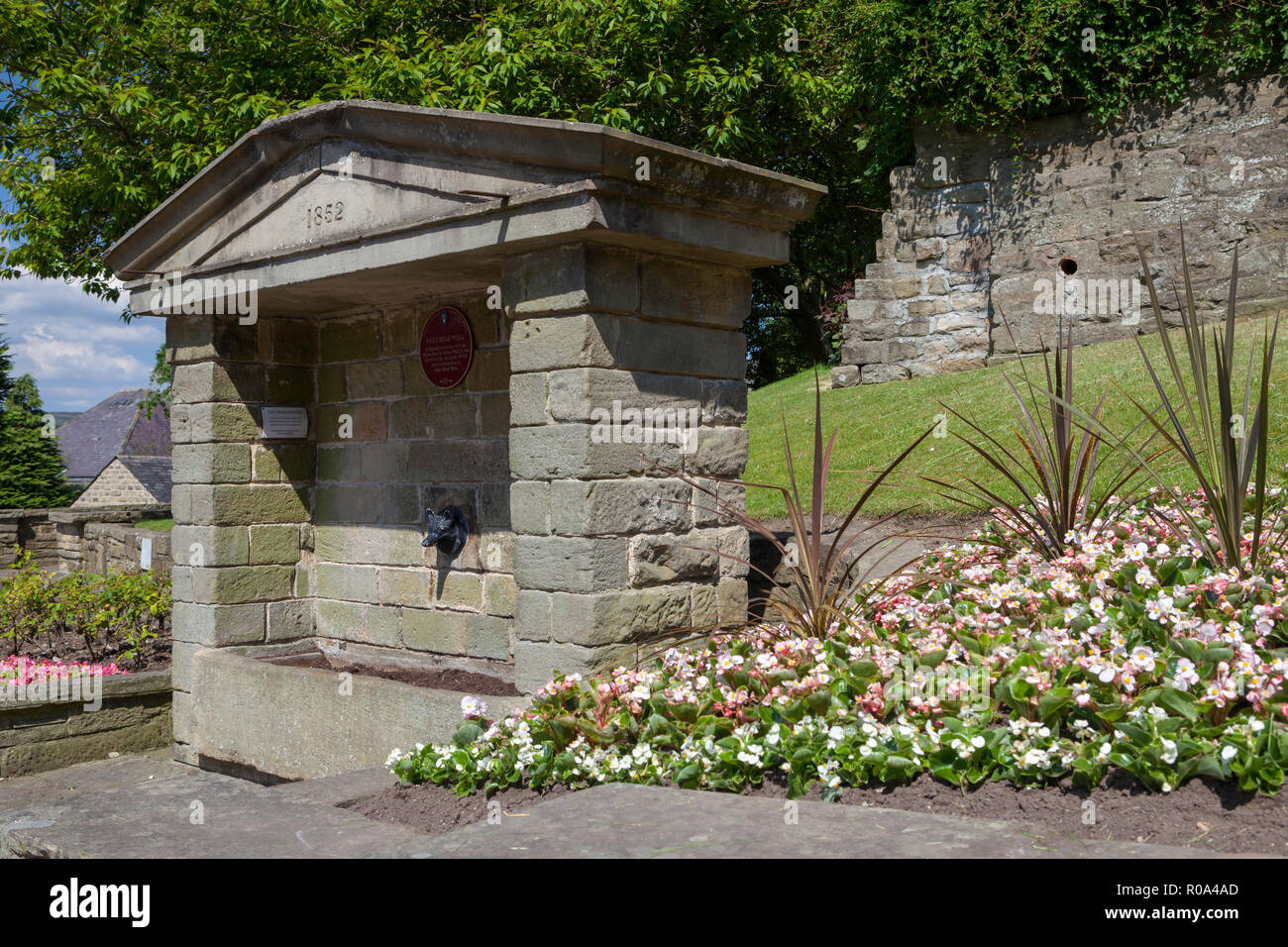 Fox's head well in Pateley Bridge, Nidderdale, Yorkshire Dales, surrounded by an attractive flower display Stock Photo