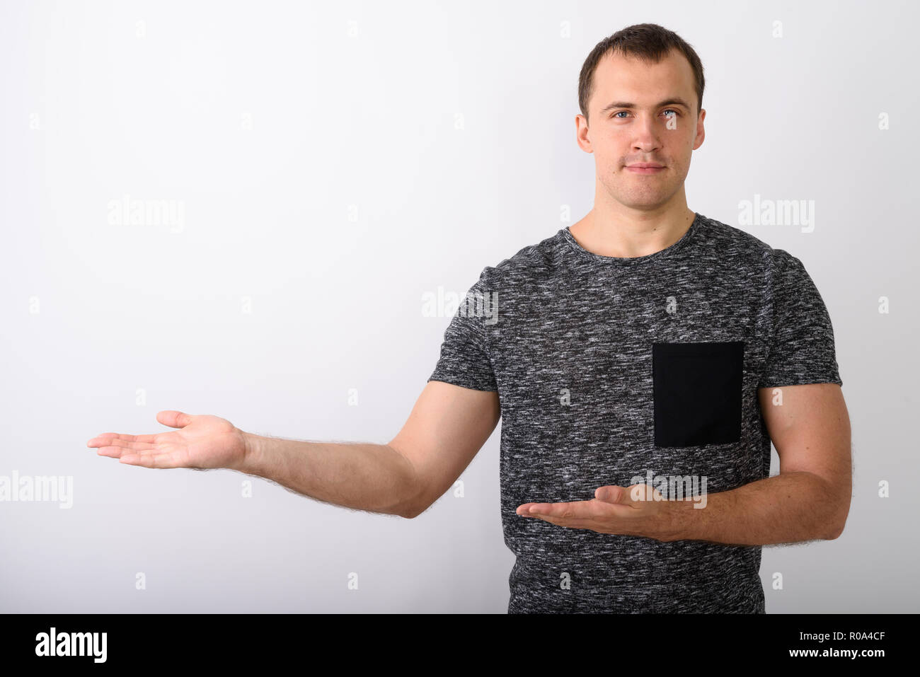 Studio shot of young muscular man showing something against whit Stock Photo