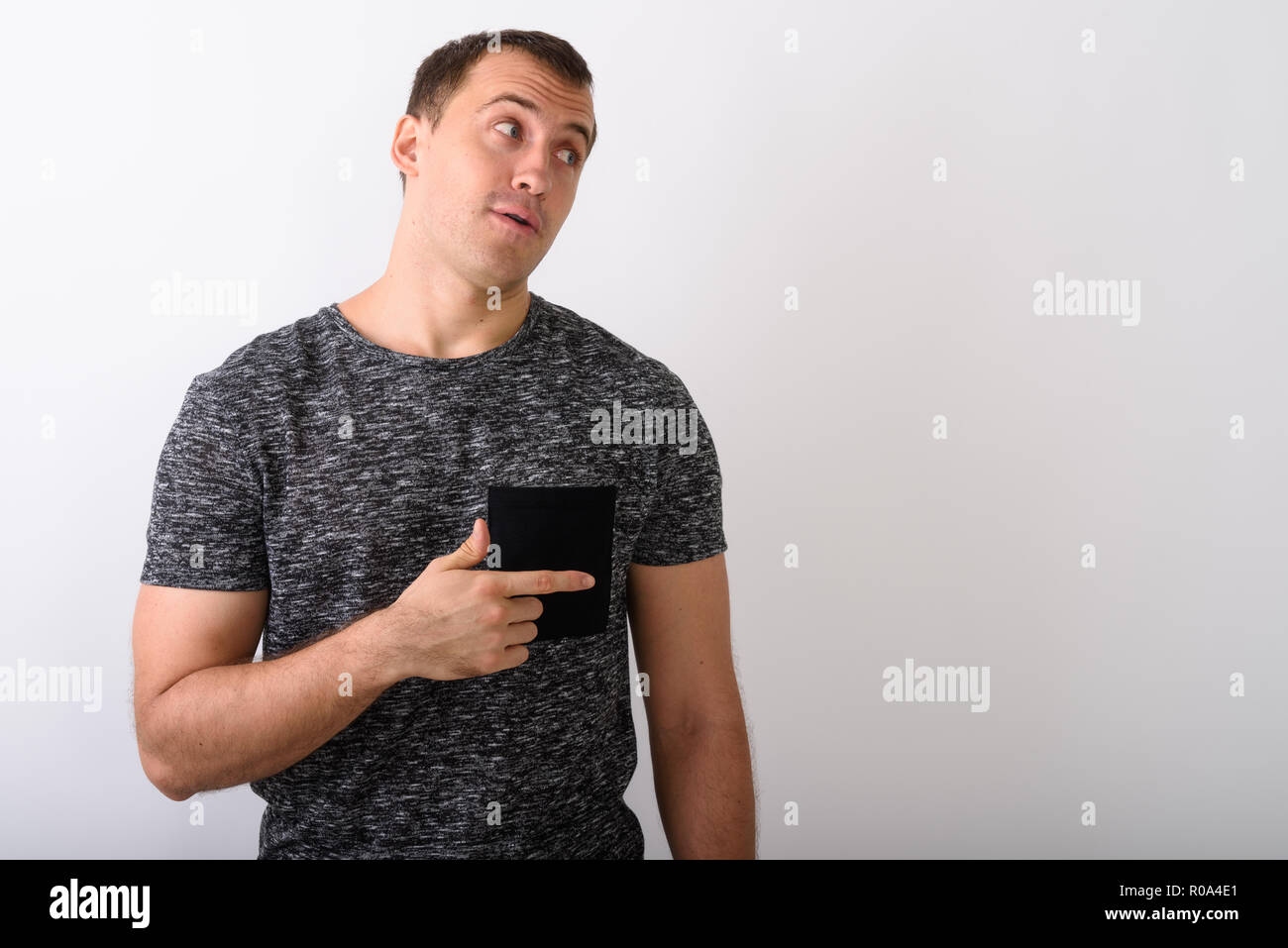 Studio shot of young muscular man thinking while pointing to the Stock Photo