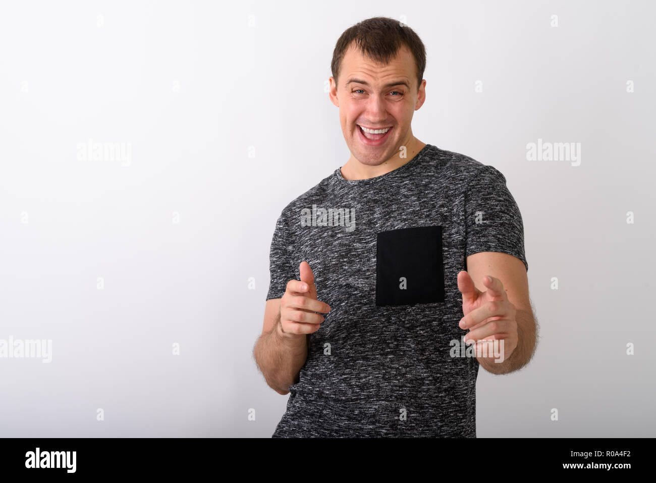 Studio shot of young happy muscular man smiling while pointing b Stock Photo