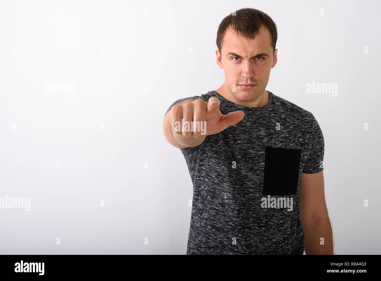 Studio shot of  angry young muscular man pointing at camera agai Stock Photo