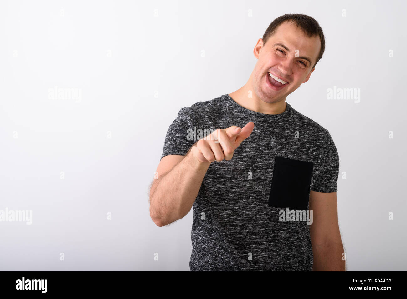 Studio shot of young happy muscular man smiling and laughing whi Stock Photo