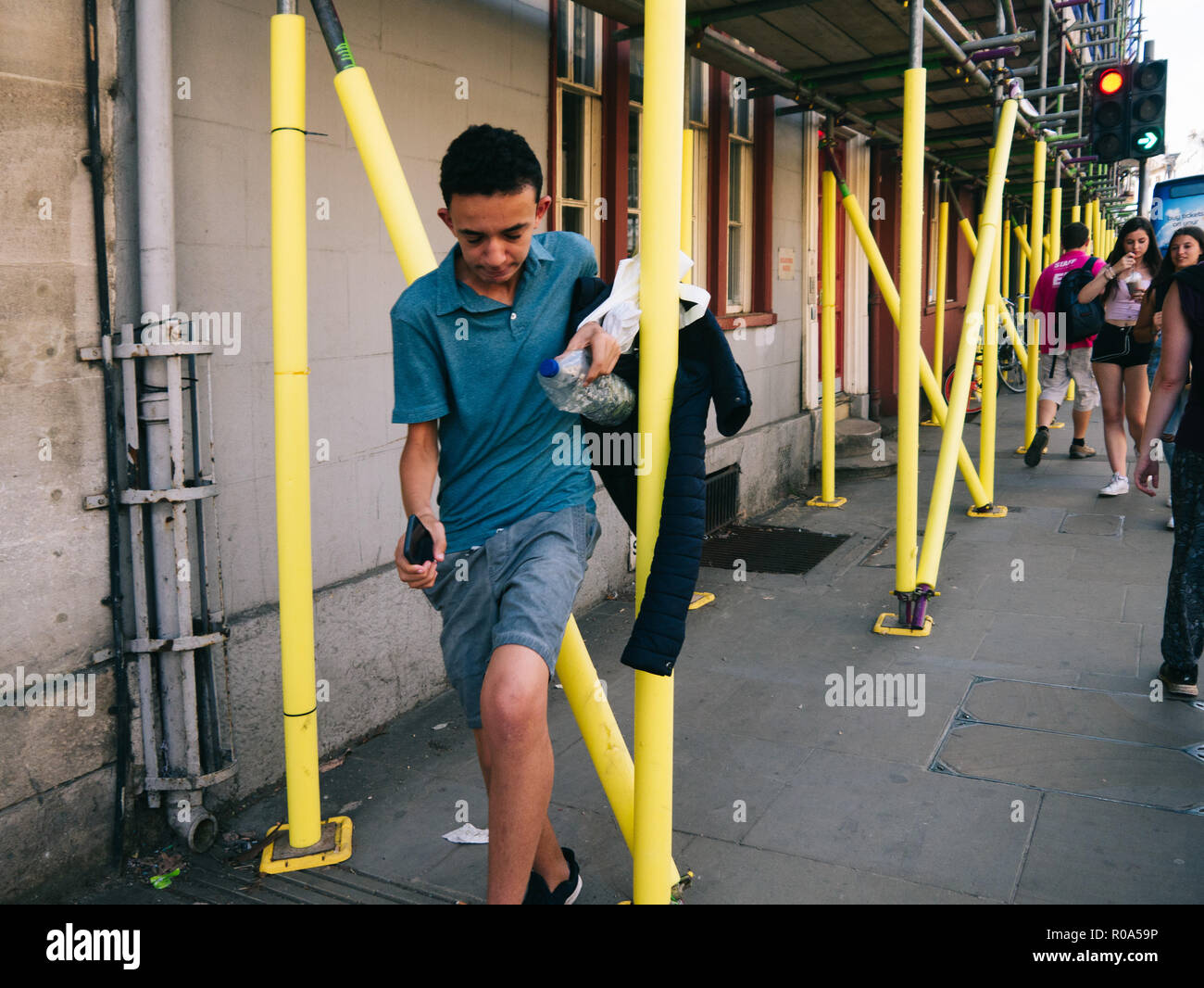 Iranian boy jumping through yellow scaffoldings in Oxford, having fun Stock Photo