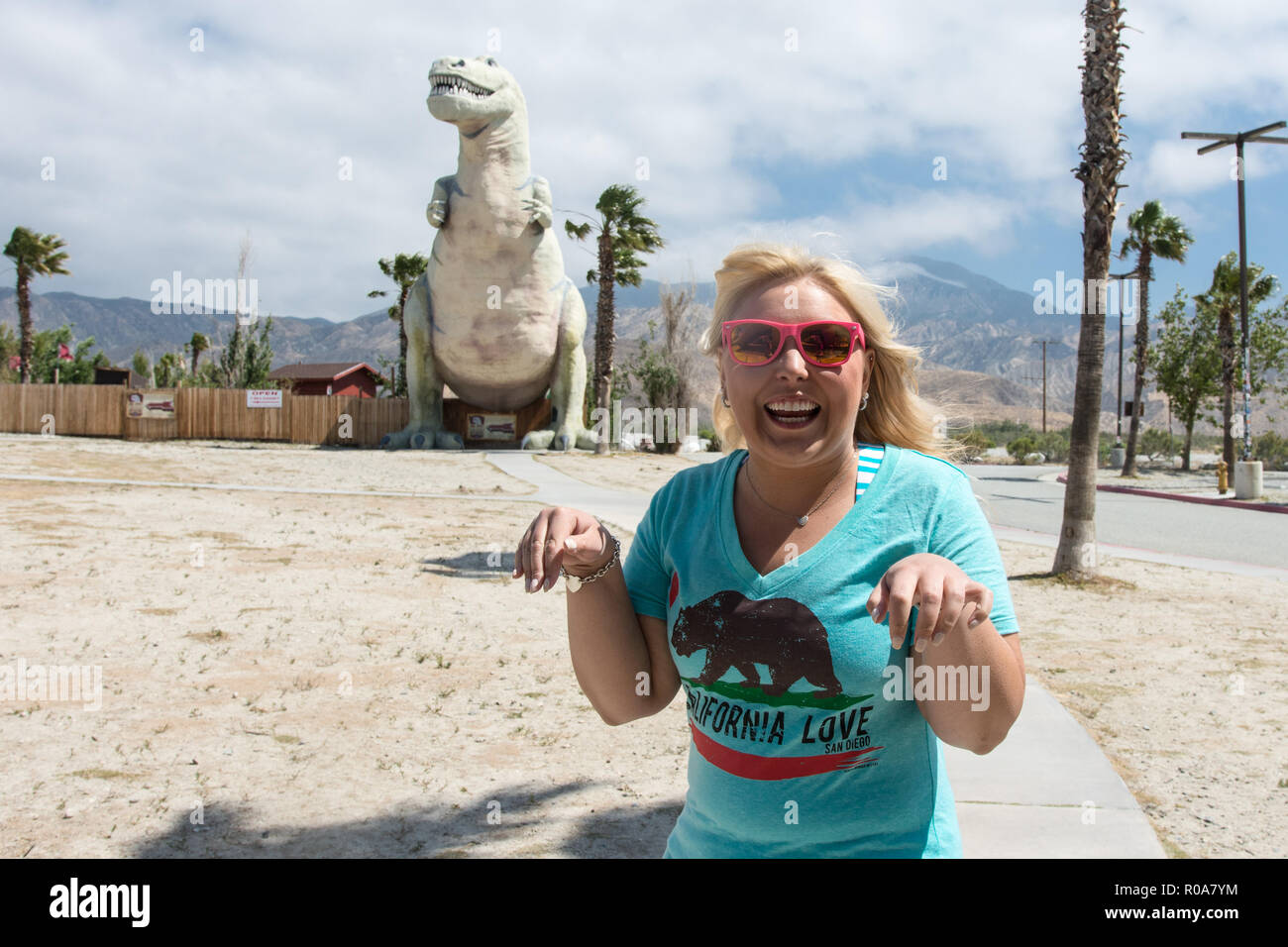 Young Woman Does T Rex Arms In Front Of The Cabazon Dinosaurs In