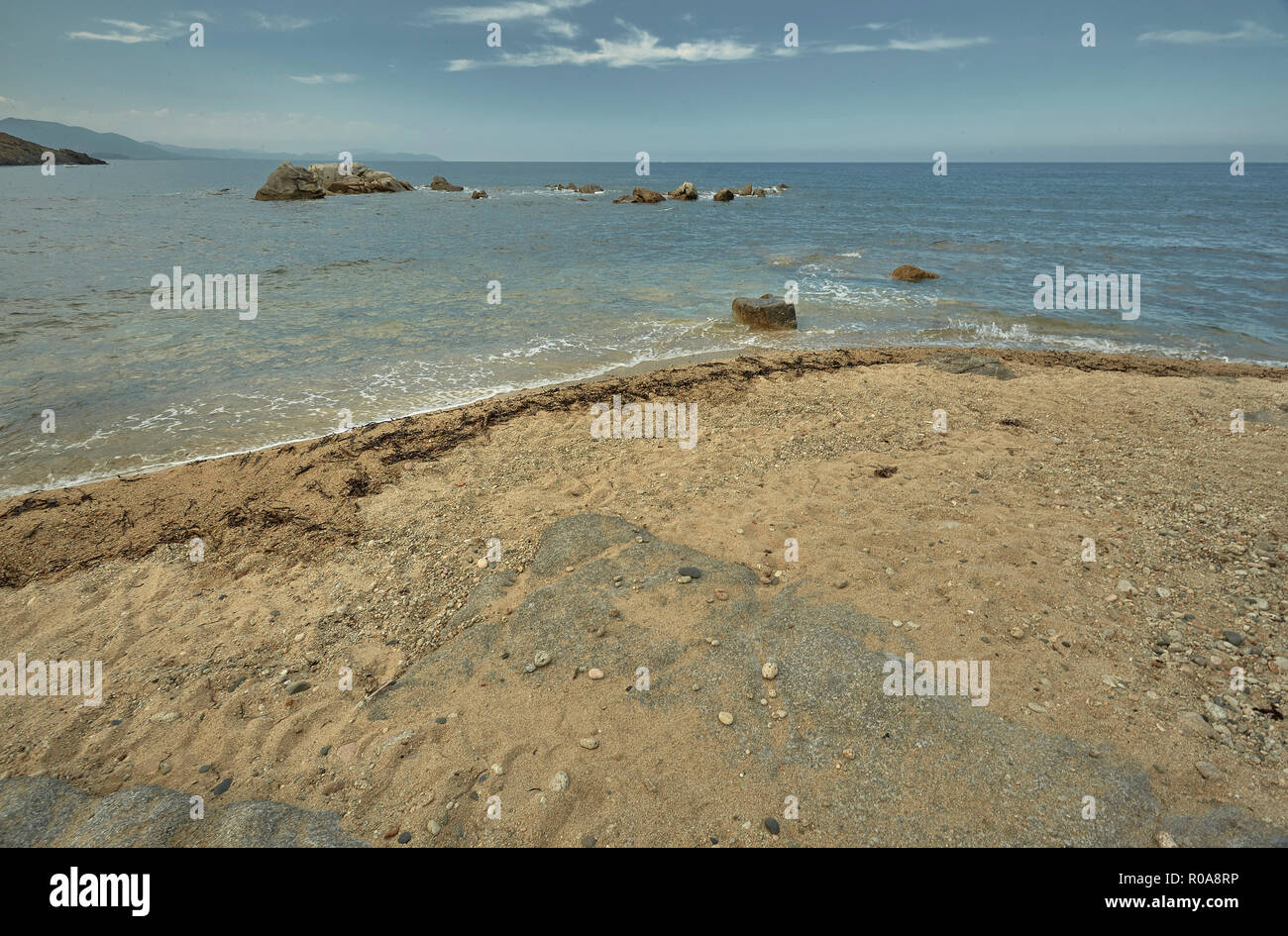 Detail of a portion of sandy beach overlooking the sea with the rocks ...