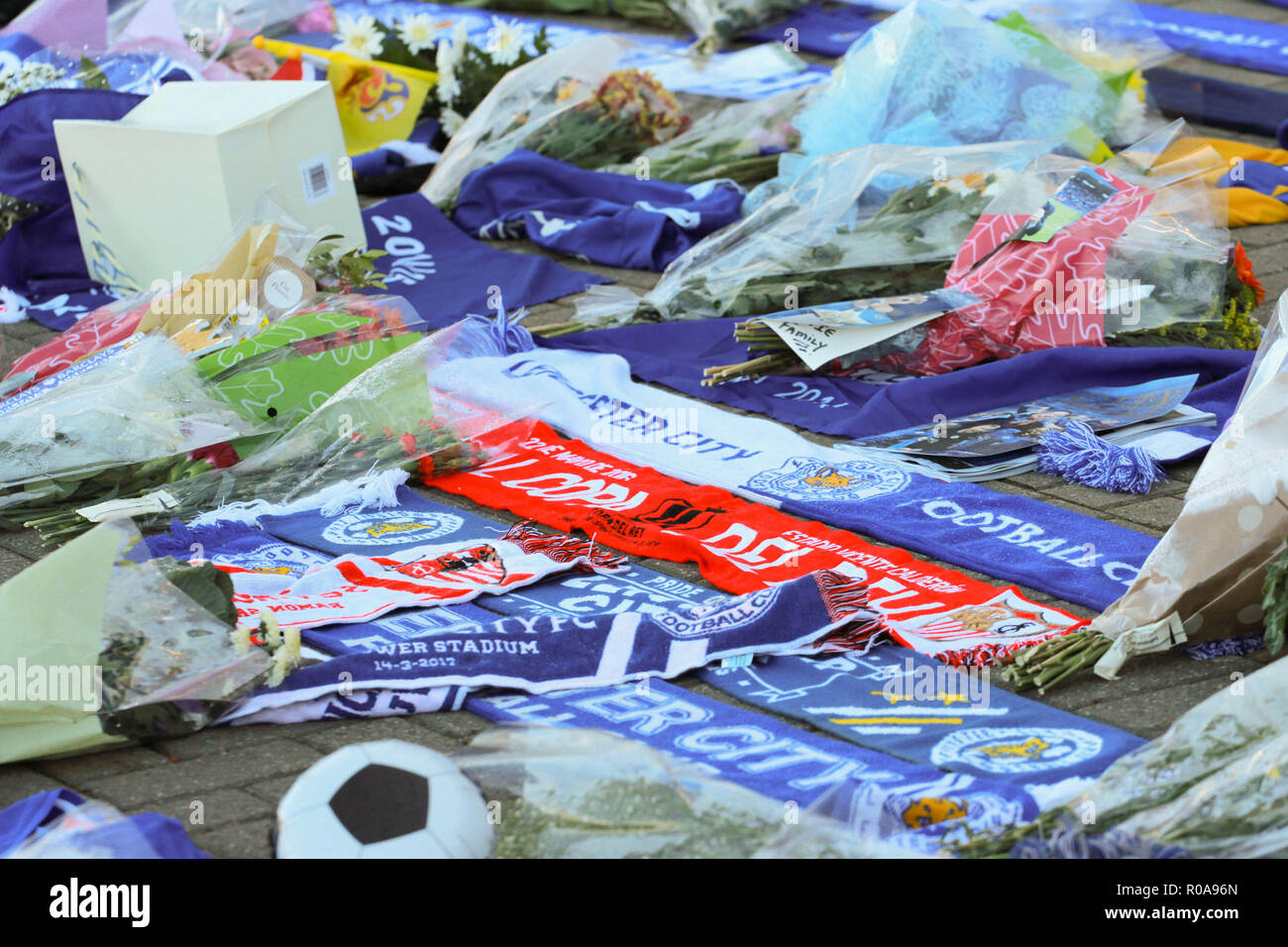 Flowers and club scurf's are seen lying on the ground during the tribute to the Leicester City chairman Vichai Srivaddhanaprabha who died in the helicopter crash. Stock Photo
