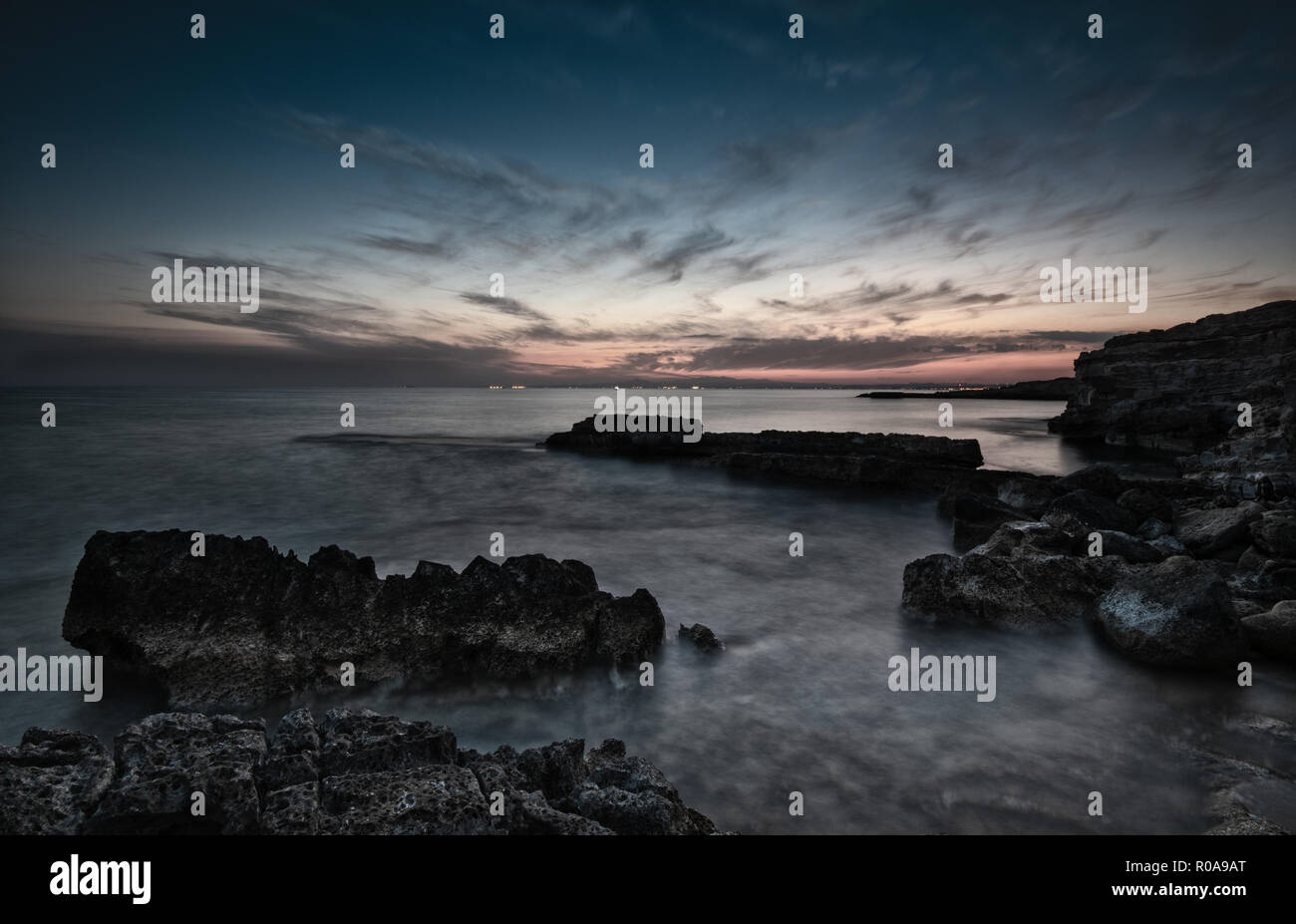 Dramatic sunset on a Rocky coastline with milky water  at Xylofagou area in Cyprus. Long Exposure image Stock Photo