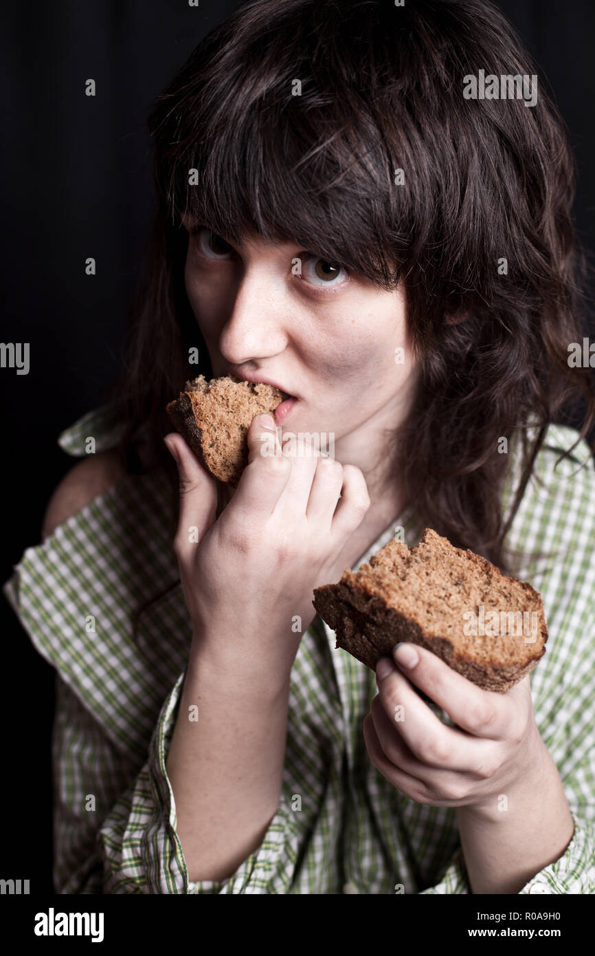 portrait of a poor beggar woman eating bread in her hands Stock Photo ...