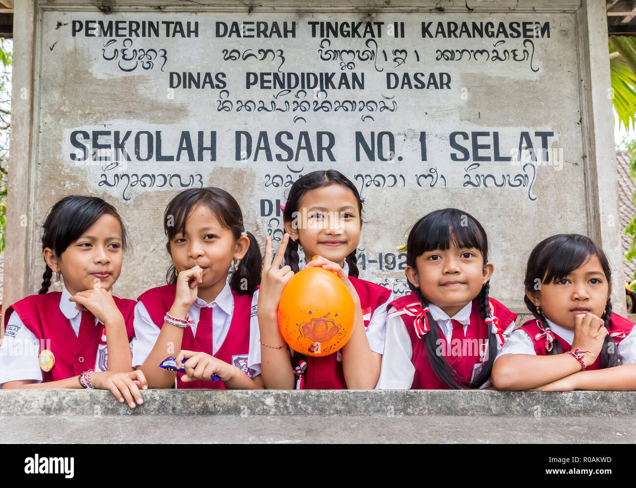 Indonesian schoolgirls in uniform posing in front of their school sign Stock Photo