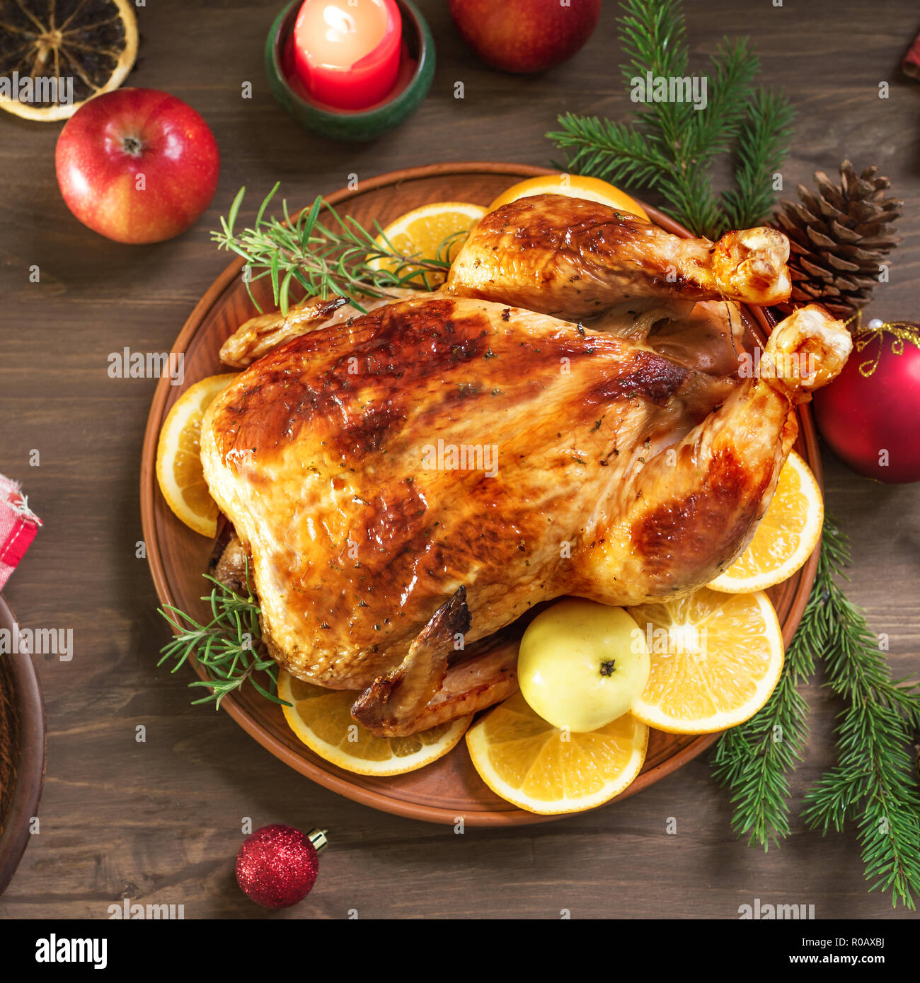 Roasted Christmas Chicken or Turkey for Christmas Dinner. Festive decorated wooden table for Christmas Dinner with baked stuffed chicken. Stock Photo
