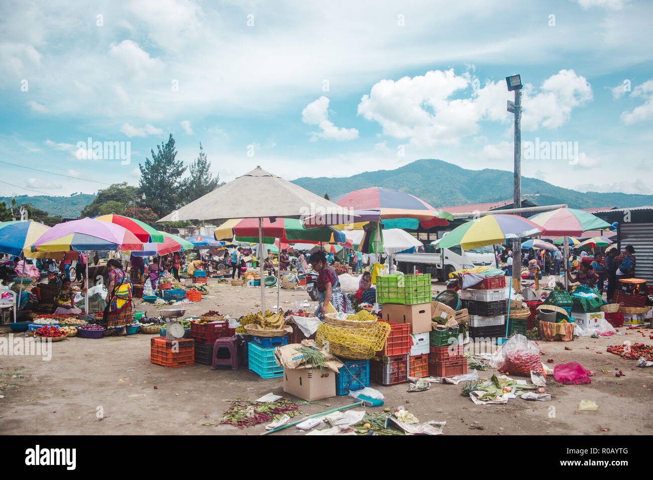 Vibrant food market stalls laid out on the floor by women in traditional Mayan dress under colorful parasol umbrellas in Antigua, Guatemala Stock Photo