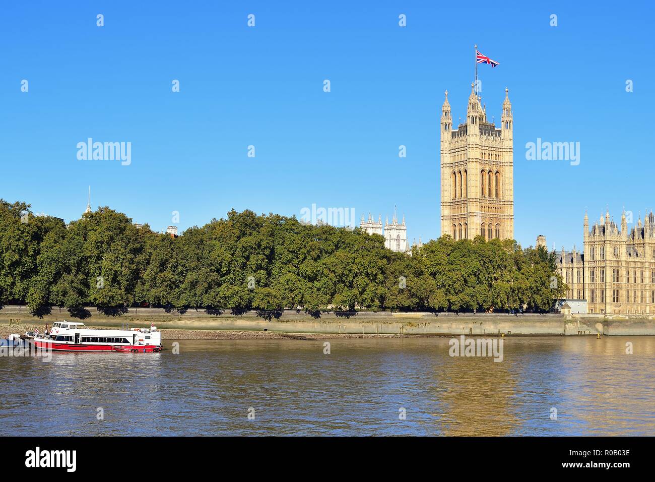 London, England, United Kingdom. Victoria Tower, with the Union Jack flying from its roof, and the Houses of Parliament beyond the River Thames. Stock Photo
