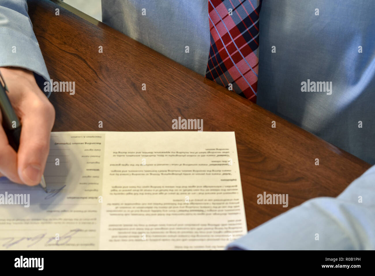 signing a paper at desk Stock Photo