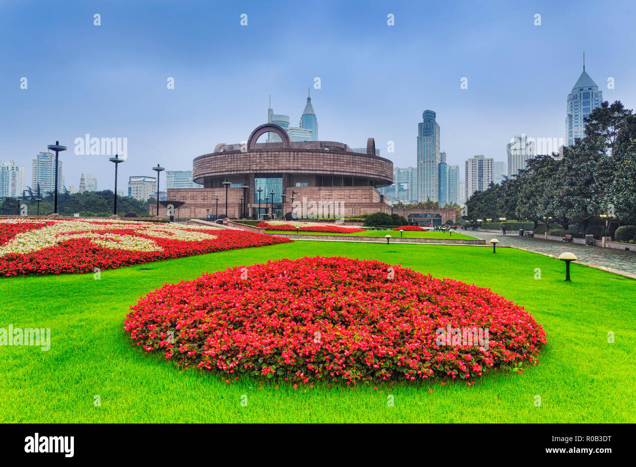 Shanghai People's square and surroundings architecture around the park in early morning. Green grass and round flowers in front of historic building. Stock Photo