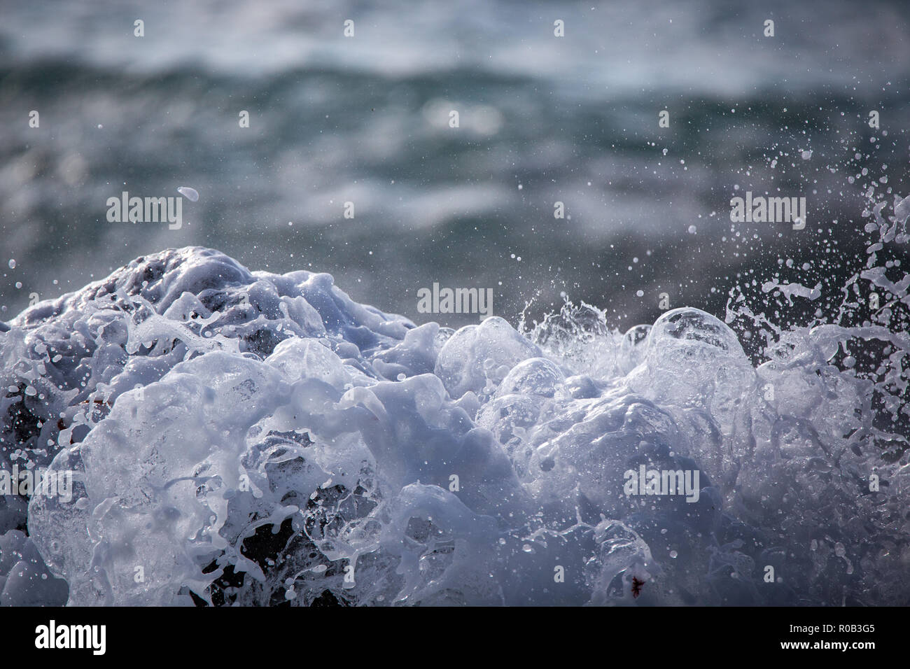 White foamy waves break over the rocks on the coastline Stock Photo